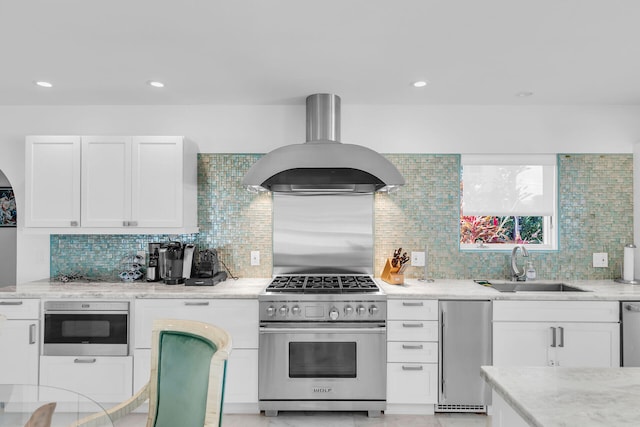 kitchen featuring white cabinetry, sink, island exhaust hood, stainless steel appliances, and light stone countertops