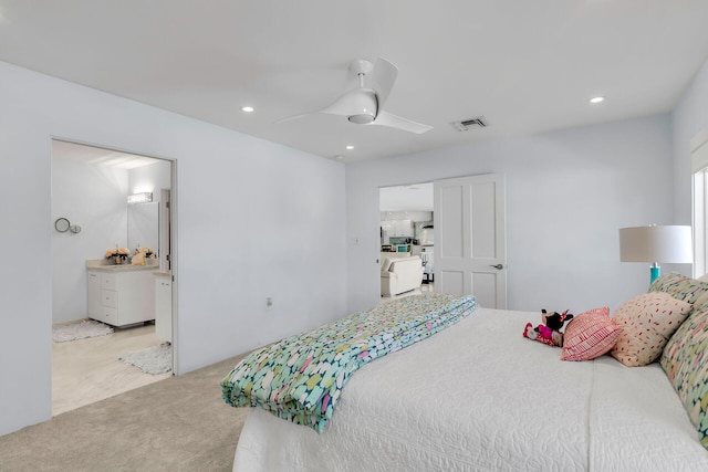 carpeted bedroom with ensuite bath and ceiling fan