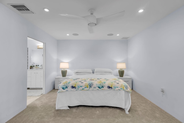 bedroom with ensuite bathroom, light carpet, and ceiling fan