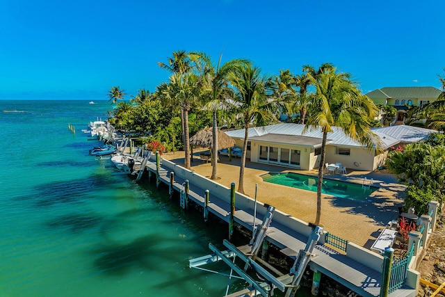 dock area with a fenced in pool, a water view, and a patio area