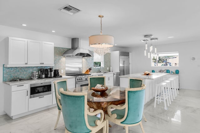 kitchen with pendant lighting, island range hood, stainless steel appliances, and a kitchen island