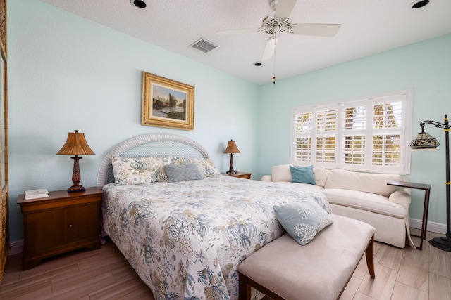 bedroom with wood finished floors, visible vents, baseboards, and a ceiling fan