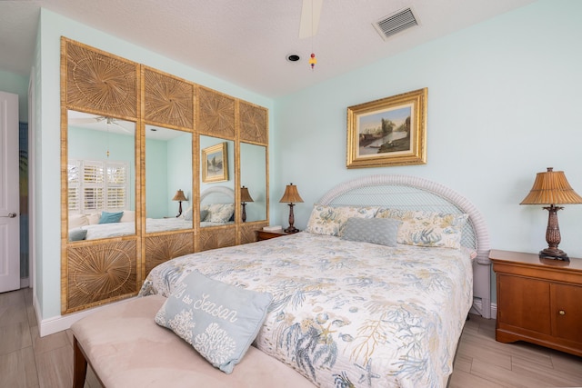 bedroom with a closet, visible vents, wood finished floors, and ceiling fan