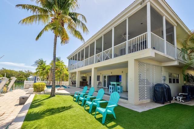 back of property with a patio, a sunroom, ceiling fan, a yard, and an outdoor pool