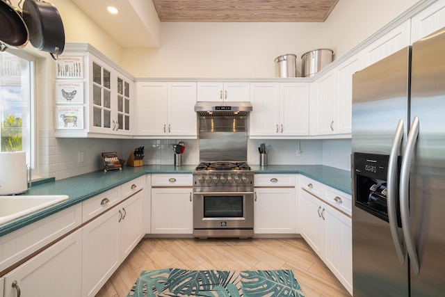 kitchen featuring glass insert cabinets, dark countertops, stainless steel appliances, white cabinetry, and backsplash