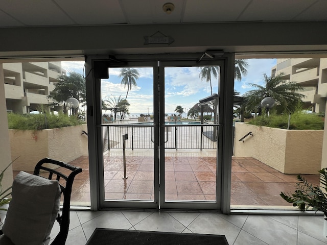 doorway to outside with a drop ceiling and light tile patterned floors