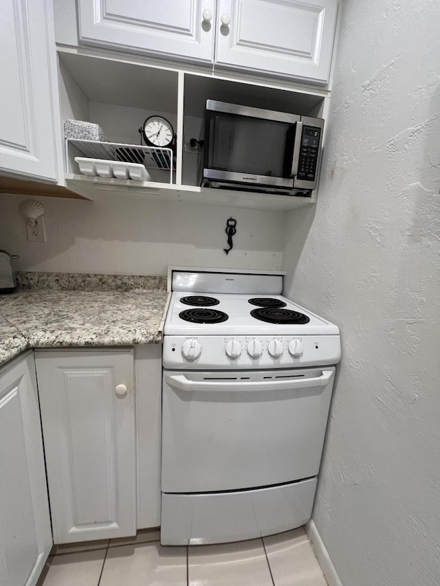 kitchen with white cabinetry, light tile patterned floors, and white electric range