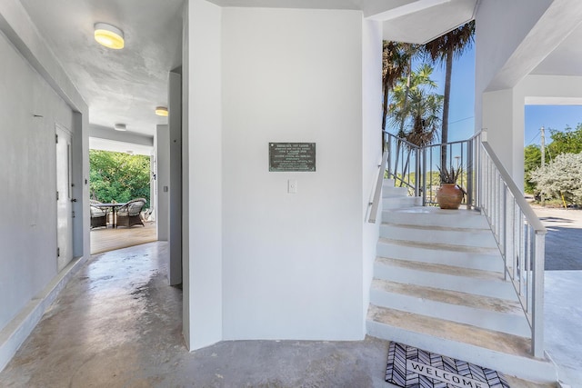 stairway featuring unfinished concrete flooring