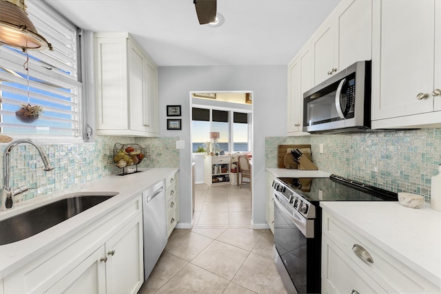 kitchen featuring appliances with stainless steel finishes, a sink, light tile patterned floors, light countertops, and decorative backsplash