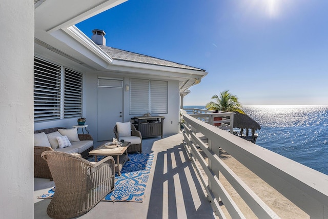view of patio with a water view, a balcony, and an outdoor living space
