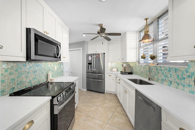 kitchen featuring appliances with stainless steel finishes, a sink, ceiling fan, backsplash, and light countertops