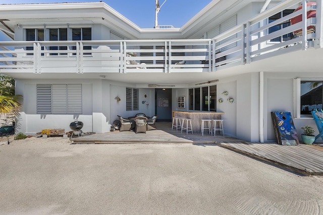 rear view of property with a balcony, a patio, and stucco siding