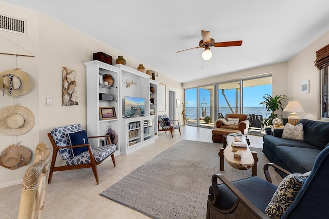 living area featuring ceiling fan, light tile patterned floors, and baseboards