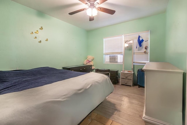 bedroom featuring ceiling fan, cooling unit, and light wood-type flooring