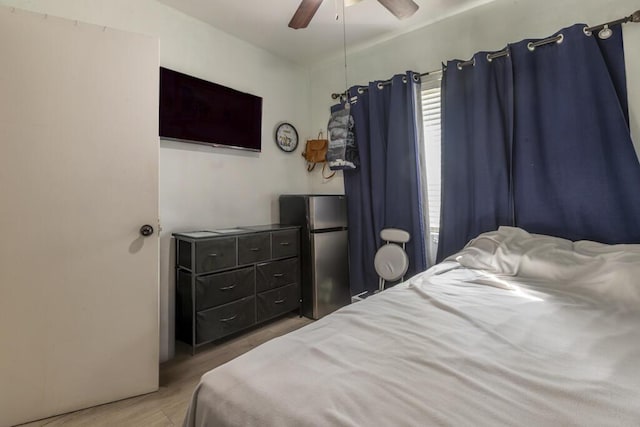 bedroom featuring ceiling fan, wood-type flooring, and stainless steel fridge