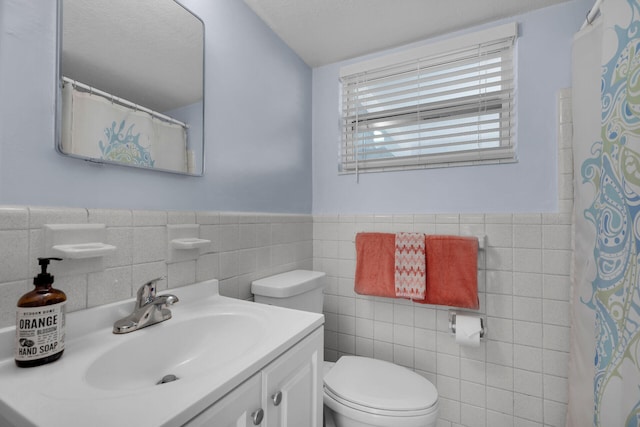 bathroom with vanity, tile walls, and toilet