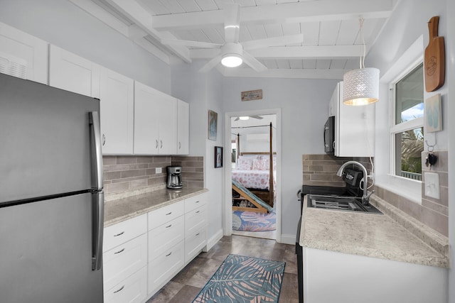 kitchen with stainless steel refrigerator, tasteful backsplash, white cabinetry, sink, and ceiling fan