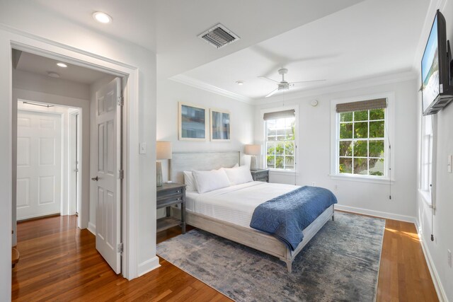 bedroom with dark hardwood / wood-style flooring, crown molding, and ceiling fan