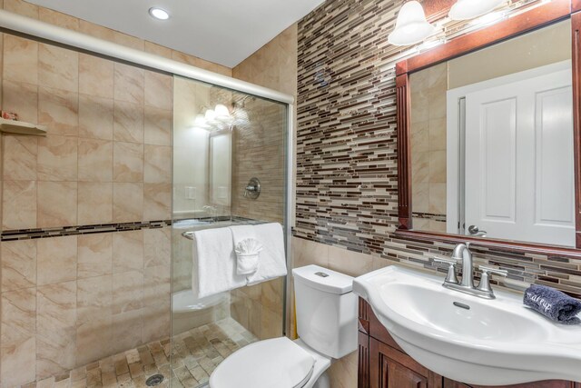 bathroom with tile walls, backsplash, vanity, walk in shower, and toilet