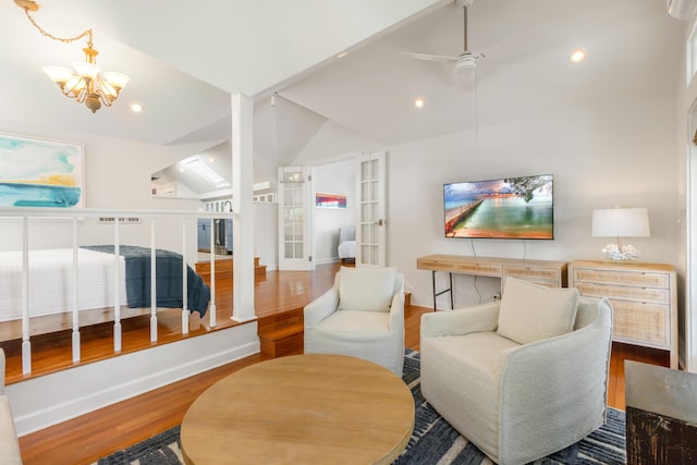 interior space with hardwood / wood-style flooring, ceiling fan with notable chandelier, vaulted ceiling, and french doors