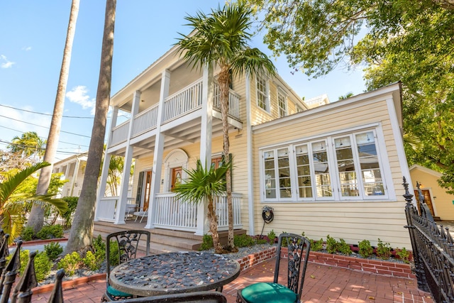 back of property featuring a balcony, covered porch, and a patio area