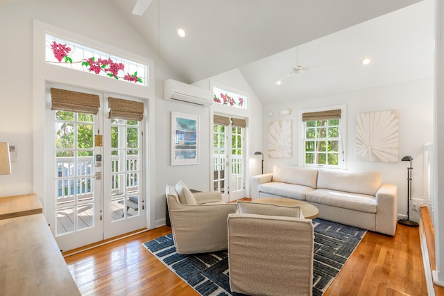 living room with a wall mounted air conditioner, hardwood / wood-style floors, french doors, and ceiling fan