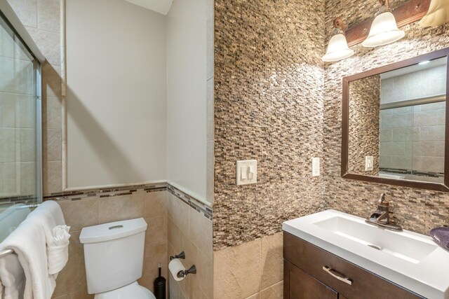 bathroom with tile walls, vanity, and toilet