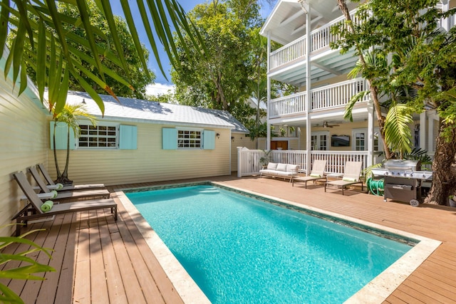 view of swimming pool with an outdoor living space, a deck, and ceiling fan