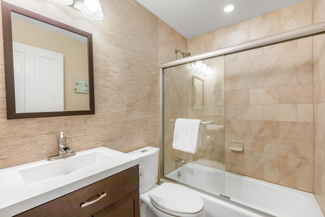 full bathroom with shower / bath combination with glass door, tile walls, vanity, decorative backsplash, and toilet