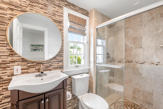 bathroom with vanity, walk in shower, decorative backsplash, and toilet