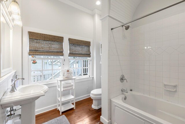 bathroom with tiled shower / bath combo, hardwood / wood-style floors, and toilet