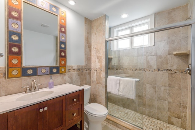 bathroom featuring walk in shower, vanity, toilet, and tile walls