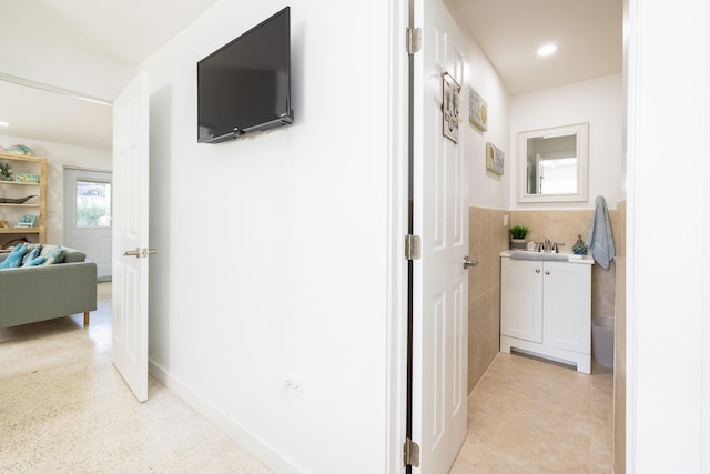 hall with sink and tile walls