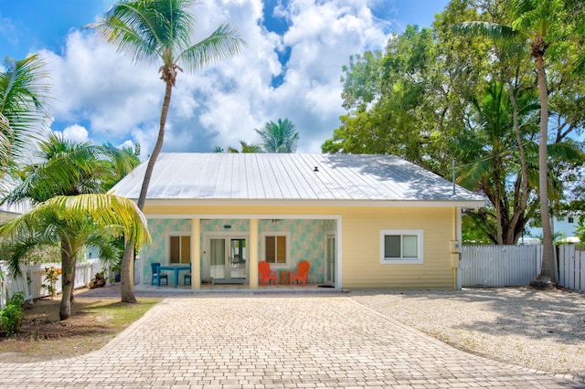 view of front of home with a porch, french doors, fence, and driveway