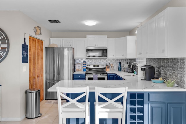 kitchen with sink, appliances with stainless steel finishes, backsplash, a kitchen breakfast bar, and white cabinets