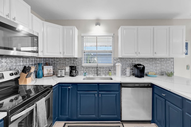 kitchen with blue cabinets, white cabinetry, sink, backsplash, and stainless steel appliances