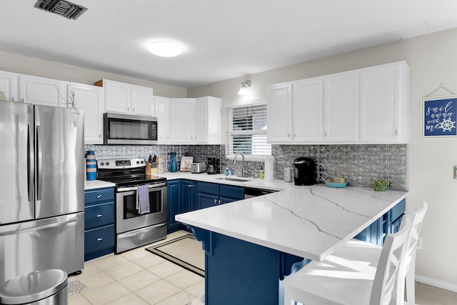 kitchen featuring sink, a breakfast bar area, blue cabinetry, stainless steel appliances, and white cabinets