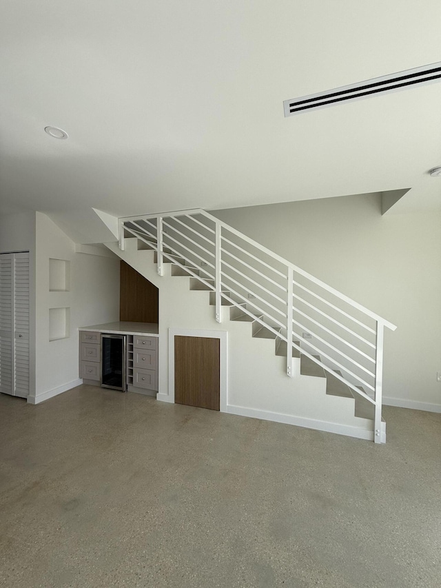 unfurnished living room featuring beverage cooler and bar area