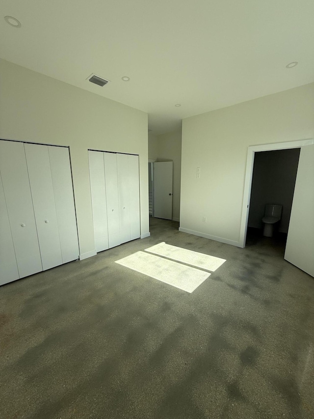 unfurnished bedroom with concrete flooring and two closets