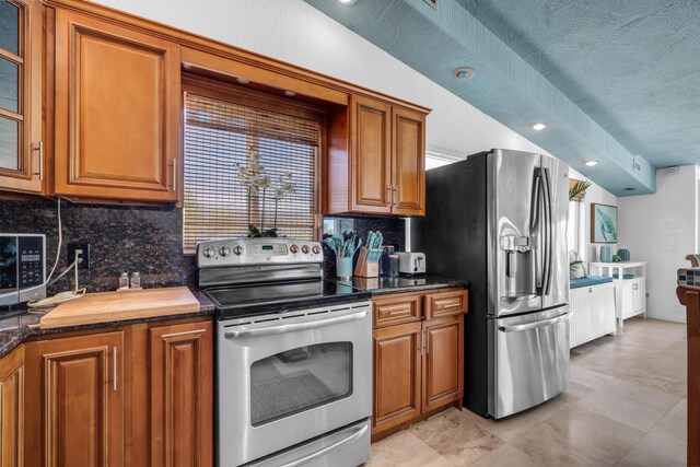 kitchen with tasteful backsplash, appliances with stainless steel finishes, dark stone countertops, and a textured ceiling