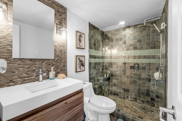 bathroom with vanity, toilet, a shower with shower door, and decorative backsplash