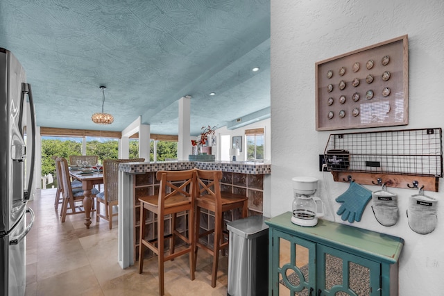 interior space featuring a wealth of natural light, kitchen peninsula, a textured ceiling, and stainless steel refrigerator with ice dispenser