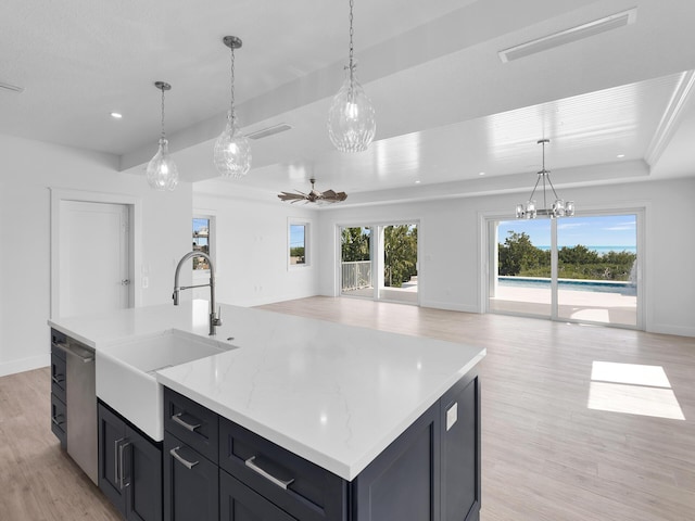 kitchen featuring pendant lighting, sink, light hardwood / wood-style floors, plenty of natural light, and a center island with sink