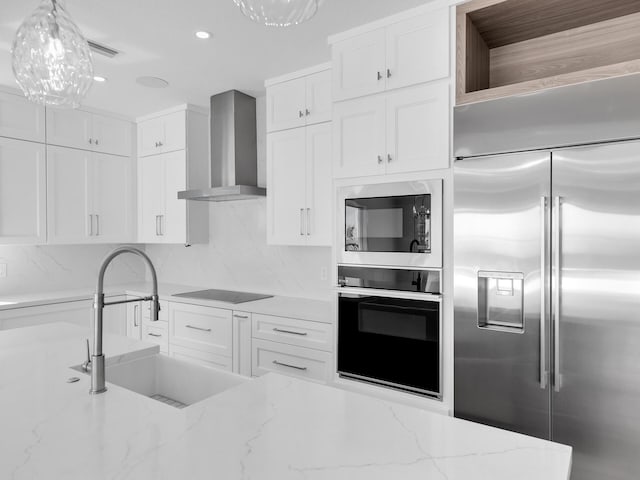 kitchen featuring wall chimney exhaust hood, sink, white cabinetry, light stone counters, and black appliances