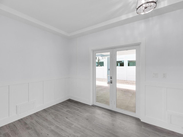 empty room featuring a chandelier, light hardwood / wood-style floors, and french doors