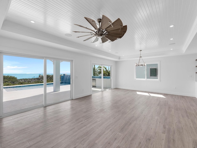 unfurnished living room with a water view, wooden ceiling, light hardwood / wood-style floors, and a tray ceiling