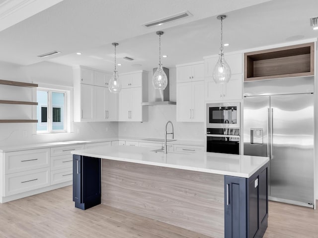 kitchen with white cabinetry, built in appliances, and an island with sink