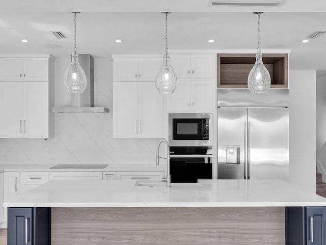 kitchen featuring white cabinetry, built in appliances, wall chimney exhaust hood, and a spacious island