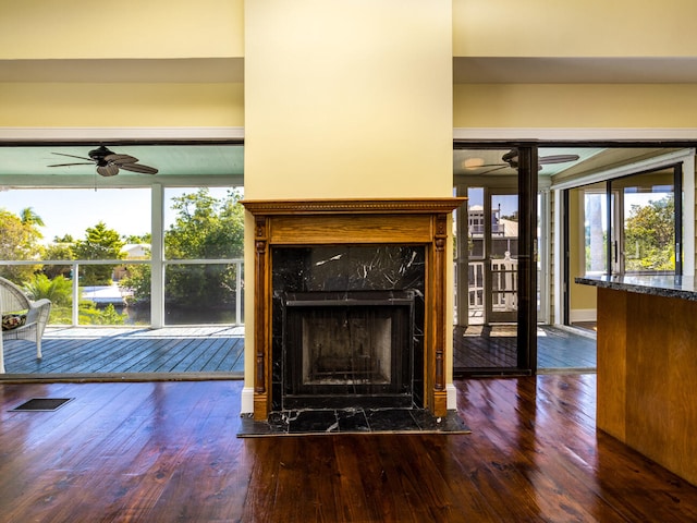 unfurnished living room with dark wood-type flooring, ceiling fan, and a fireplace