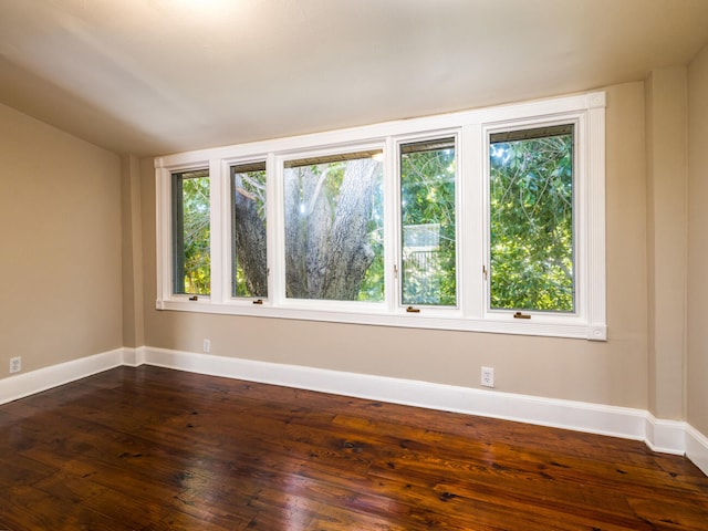 spare room with dark hardwood / wood-style flooring and vaulted ceiling